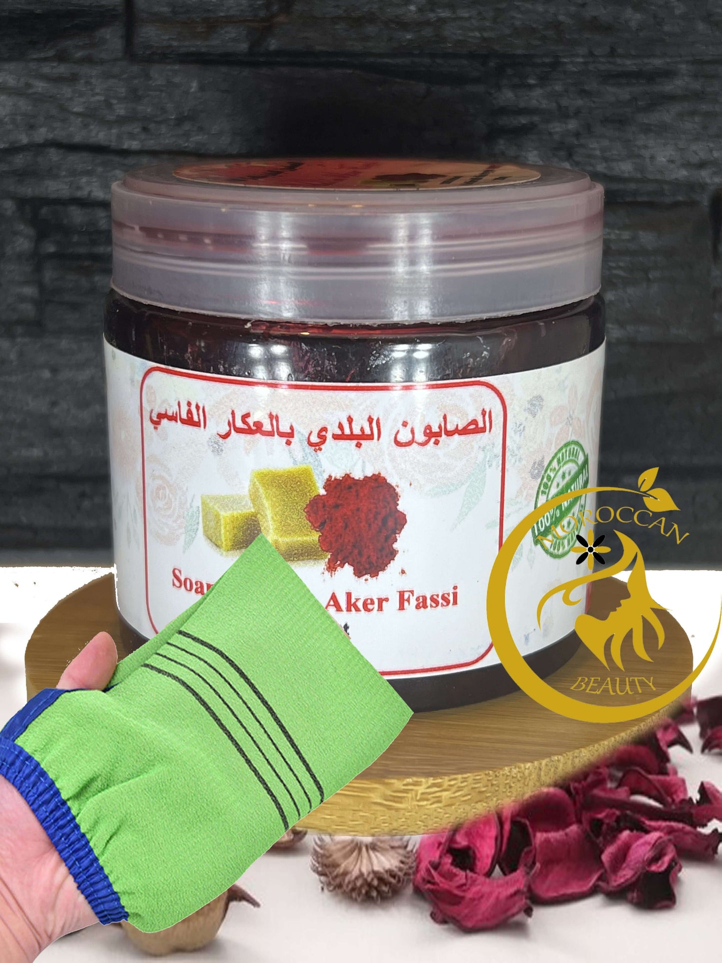 Moroccan black soap with Aker Fessi and green scrub glove on display with dried rose petals.