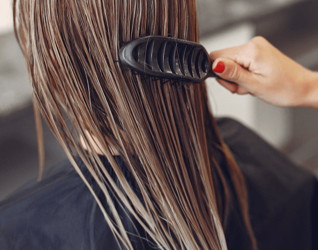 Woman brushing long, wet hair promoting healthy hair growth and scalp care.